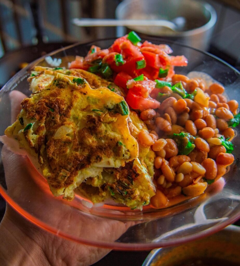 Delicious omelet served with beans and fresh salsa on a clear plate.