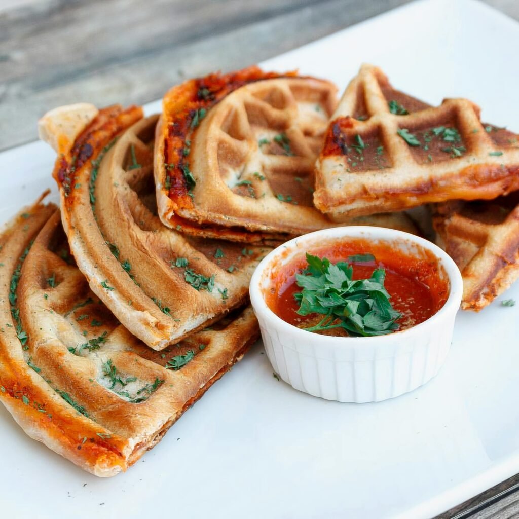 Crispy waffle pizza slices served with delicious marinara sauce, sprinkled with herbs.